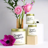 Large and mini Ginger Hibiscus scented soy candles pictured with vase and flowers.