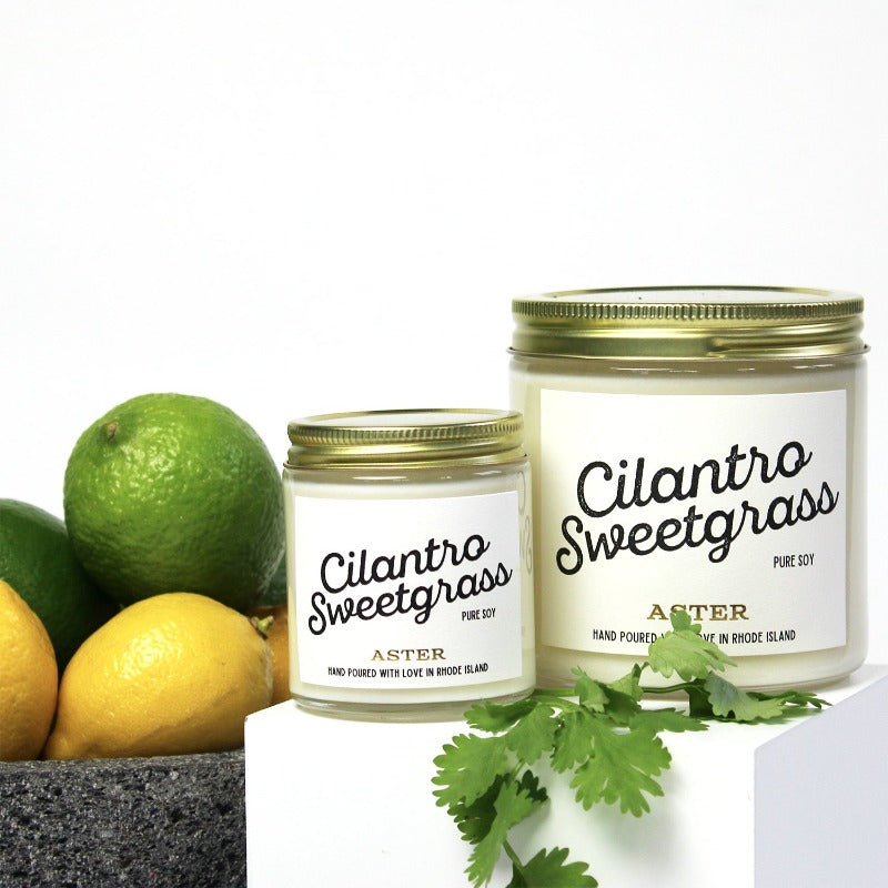 Large and mini Cilantro Sweetgrass scented soy candles pictured with bowl of lemons and limes.